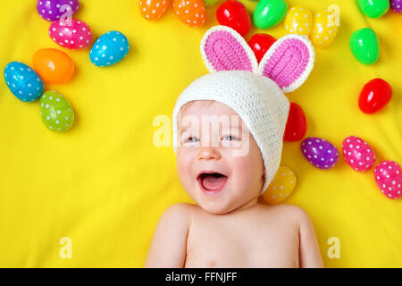 Baby Boy in bunny hat lying on couverture jaune avec des oeufs de pâques Banque D'Images