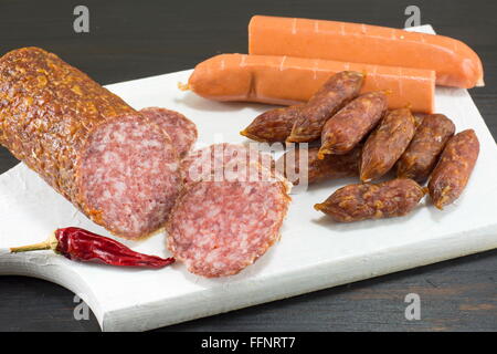 Saucisses et hot-dogs en tranches sur une planche à découper blanc Banque D'Images