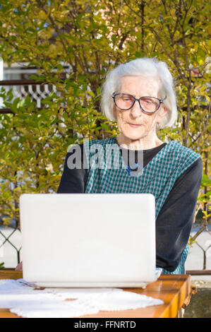 Femme de 90 ans ayant un appel vidéo sur un ordinateur portable blanc Banque D'Images