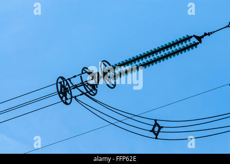 Close-up de l'isolant électrique sur les lignes électriques à haute tension, avec panneaux de câbles vers le bas, contre le ciel bleu. Banque D'Images