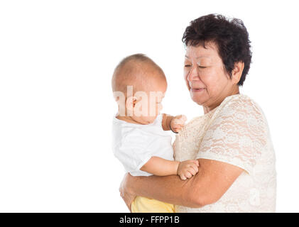 Grand-mère de l'Asie en prenant soin d'un petit-enfant, isolé sur fond blanc. Banque D'Images