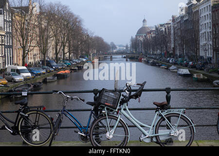 Les vélos garés le long de la balustrade contre Canal Singel à Amsterdam en hiver aux Pays-Bas Banque D'Images