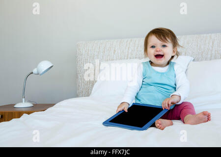 Adorable Bébé holding a tablet smiling at the camera Banque D'Images