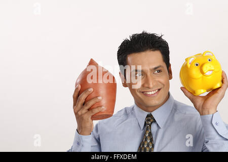 Businessman holding petit pot en terre d'économie dans une main et le plastique tirelire dans d'autres part M.# 703T Banque D'Images