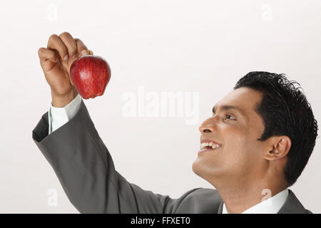 Businessman holding Red Apple dans l'index avec le pouce de la main droite M.# 703T Banque D'Images