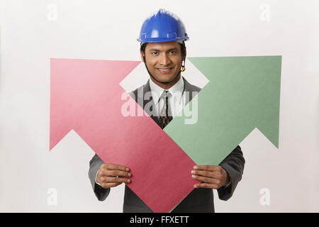 Businessman wearing blue casque avec holding big size papier couleur vert et rouge flèche dans les deux mains MR# 703T Banque D'Images