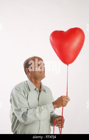Vieil homme regardant vers le haut en forme de coeur en ballon à gaz MR3# 703I Banque D'Images