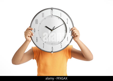 Boy holding wall clock en face de son visage avec la main MR# 703V Banque D'Images