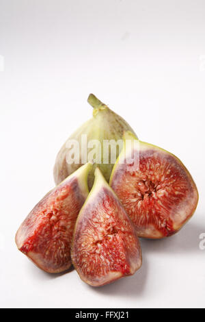 Fruit , fig Ficus carica Anjir un plein et un autre coupé en trois morceaux de texture juteuse rouge sur fond blanc Banque D'Images