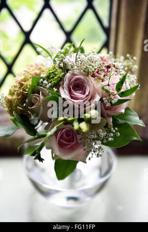 Un joli bouquet de roses roses dans un petit vase à un mariage Banque D'Images