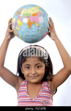 Les Indiens de l'Asie du Sud six year old girl holding globe on head looking at camera MR# 364 Banque D'Images