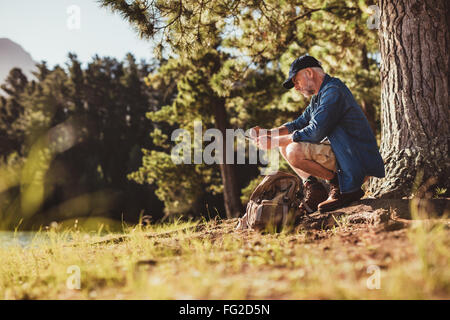 Portrait of senior hiker contrôler sa boussole. Young par un arbre à la recherche de direction. Banque D'Images