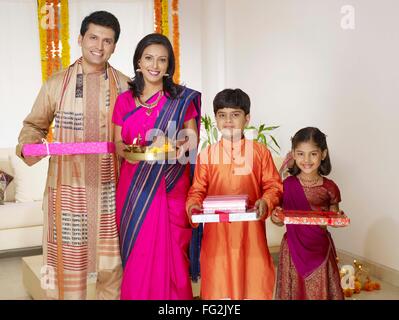 Mother holding pooja thali avec family holding gift boxes standing in house M.# 702R,MR# 702S,MR# 702T,MR# 702U Banque D'Images