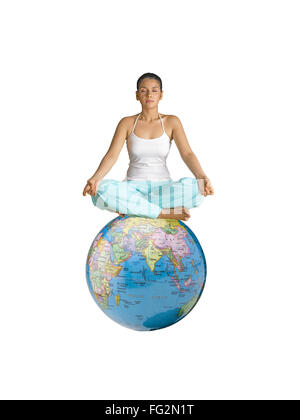 Dame faisant du yoga assis sur globe MR Banque D'Images