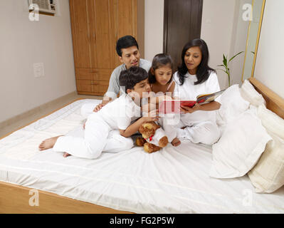 Les parents avec enfants lecture livre assis sur le lit dans la chambre M.# 702R,MR# 702S,MR# 702T,MR# 702U Banque D'Images