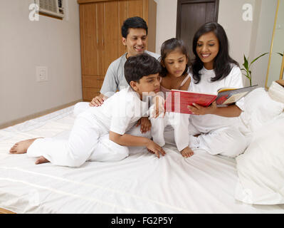 Les parents avec enfants lecture livre assis sur le lit dans la chambre M.# 702R,MR# 702S,MR# 702T,MR# 702U Banque D'Images