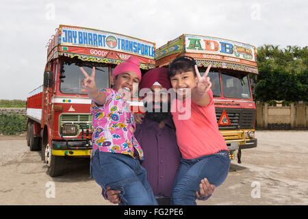 Homme Sikh transportant des enfants debout devant des camions M.# 779A, 702X;702Y Banque D'Images