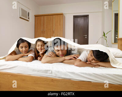 Les parents ayant des enfants en drap de lit dormir sur lit dans la chambre M.# 702R,MR# 702S,MR# 702T,MR# 702U Banque D'Images