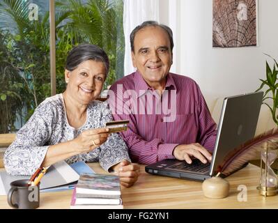 Vieux couple travaillant ordinateur portable avec carte de crédit montrant M.# 702T, 702S Banque D'Images