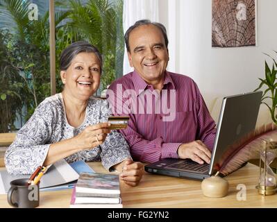 Vieux couple travaillant ordinateur portable avec carte de crédit montrant M.# 702T, 702S Banque D'Images