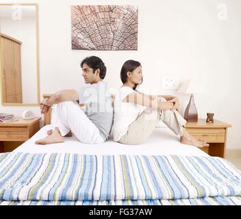 Jeune homme femme assis dos à dos sur le lit MR# 702V, 702U Banque D'Images