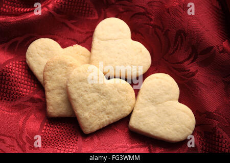 Biscuits sablés en forme de coeur sur un tissu rouge Banque D'Images