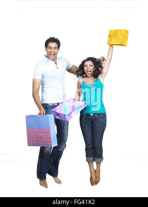 Les Indiens de l'Asie du Sud man and woman holding shopping bags and jumping with joy M. Banque D'Images