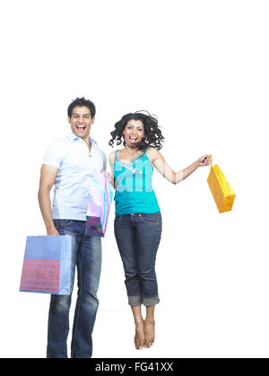 Les Indiens de l'Asie du Sud man and woman holding shopping bags and jumping with joy M. Banque D'Images