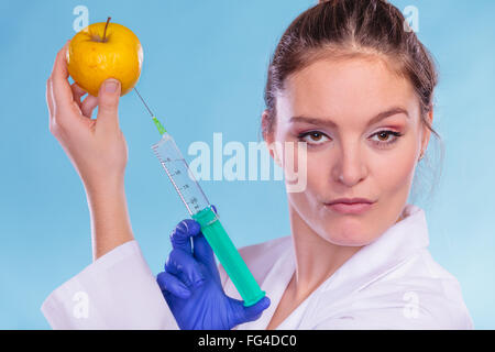 L'injection de médecin chercheur apple avec seringue. Chimiste holding fruits génétiquement modifiés. Modification des aliments GM. Banque D'Images