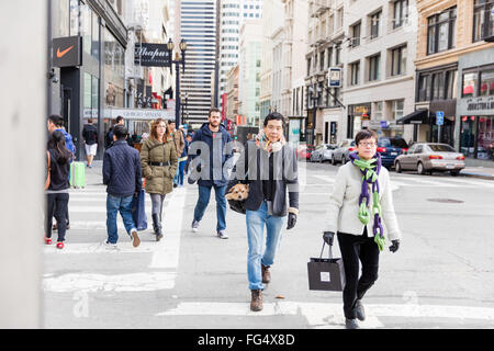 Les personnes qui traversent une rue - Asian couple wearing scarf, homme portant un chien dans le sac à main, femme portant un sac shopping Banque D'Images