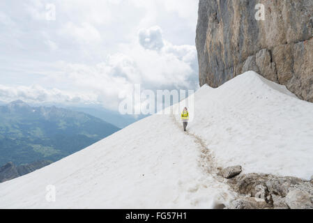 Male hiker de marcher à travers un champ de neige sous le sommet falaise de la Tournette randonnée au lac d'Annecy en Savoie,France Banque D'Images