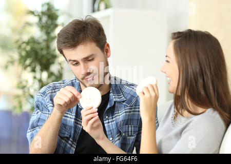 Couple et la souffrance régime avec petite amie offrant un cookie en diététique et le petit ami dégoûté Banque D'Images