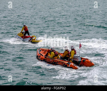 Un bateau gonflable rigide et d'un scooter de la RNLI patroling la côte en mer Banque D'Images