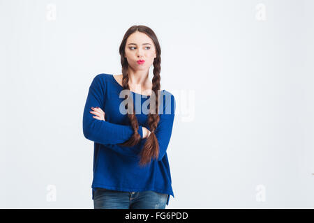 Pensive woman avec deux longues tresses debout avec les bras croisés et de penser sur fond blanc Banque D'Images