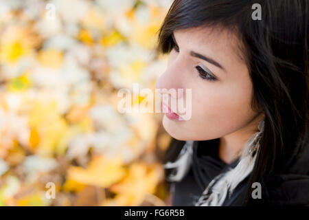 Un jeune autochtone modèle féminin vus du dessus a un triste et lointain contemplative regardez, à la recherche de l'appareil photo à l'extérieur en paramètre d'automne Banque D'Images