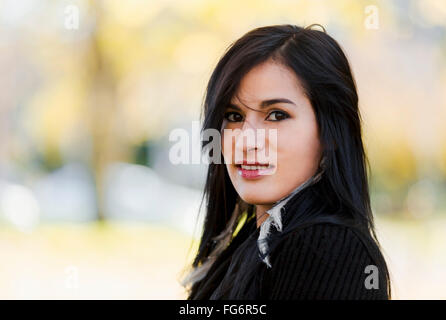 Un jeune autochtone modèle féminin sourit et regarde la caméra dans un headshot les épaules jusqu'à l'extérieur prises à l'automne Banque D'Images