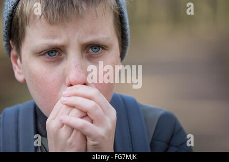 Un garçon froid dans les bois en essayant de garder au chaud Banque D'Images