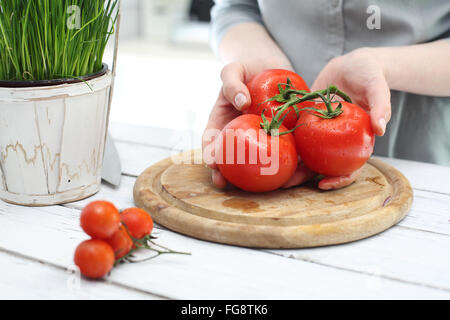 Tomate, femme préparant un repas. Petit ou grand ? La saveur de la tomate. Légumes, tomates rouges dans la cuisine Banque D'Images