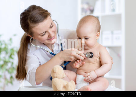 Cute femme pédiatre examinant de baby kid with stethoscope Banque D'Images