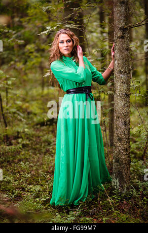 Long-hair girl en robe verte à la forêt. Banque D'Images