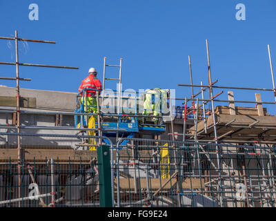 Deux travailleurs de la construction comité permanent sur l'échafaudage, travaillant sur une passerelle. Banque D'Images