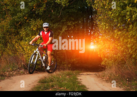 L'homme est le vélo en forêt d'automne Banque D'Images