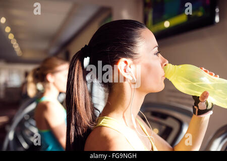 Jolie femme dans la salle de sport sur l'eau potable de tapis roulant Banque D'Images