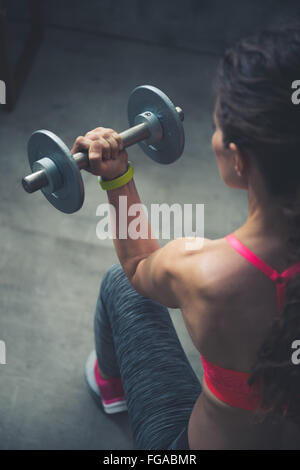 Le corps et l'esprit de l'exercice dans loft studio de remise en forme. Vu de dos femme fitness haltère de levage Banque D'Images