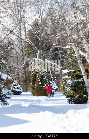Woman in Red Jacket prend son petit chien (shih tzu) dans une forêt ou dans une région rurale dans la neige profonde dans le Nord de l'Ontario, Canada Banque D'Images