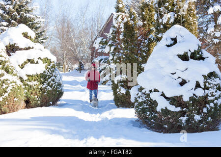 Woman in Red Jacket prend son petit chien (shih tzu) dans une forêt ou dans une région rurale dans la neige profonde dans le Nord de l'Ontario, Canada Banque D'Images
