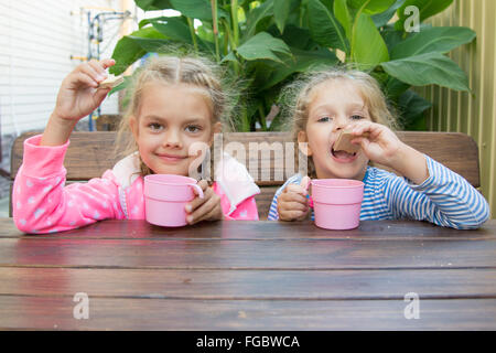 Deux filles soeur assis à une table en bois sous le porche, et le petit déjeuner Banque D'Images