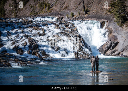 Deux hommes la pêche à la mouche dans une rivière près d'une petite cascade Banque D'Images