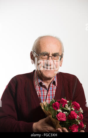 Ancien senior man holding bouquet de roses rouges wearing red sweater Banque D'Images