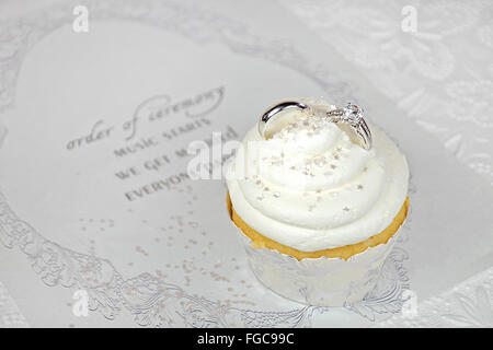 Les anneaux de mariage en cupcake cerise sur invitation de mariage contemporain Banque D'Images